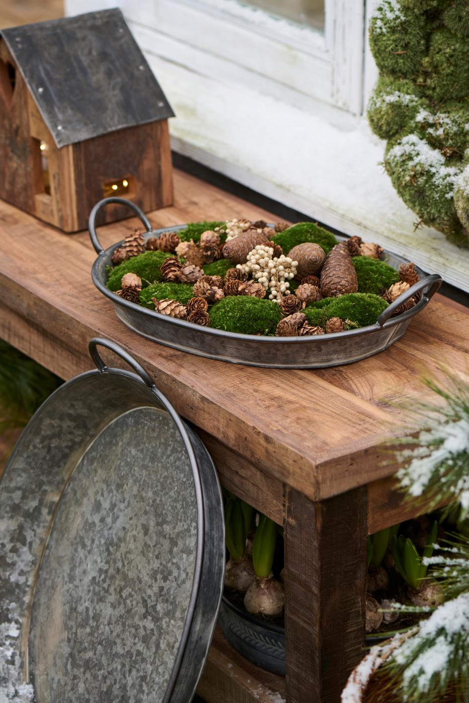 Oval Urban Garden-brett med mose, kongler og naturmaterialer som vinterdekorasjon på et trebord