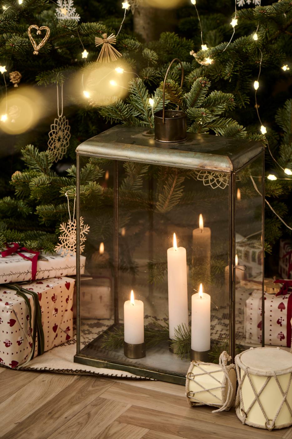 Magnetiske lysestaker med kronelys i glasslanterne pyntet med gran ved juletreet
