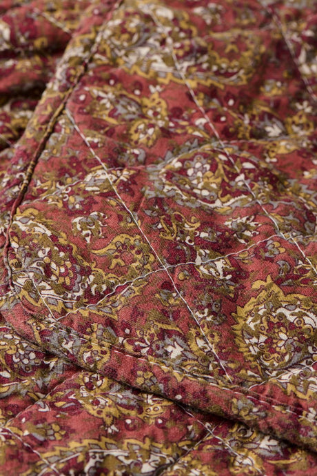 Nærbilde av quilt fra Ib Laursen med detaljert paisleymønster i varme rosa og grønne farger