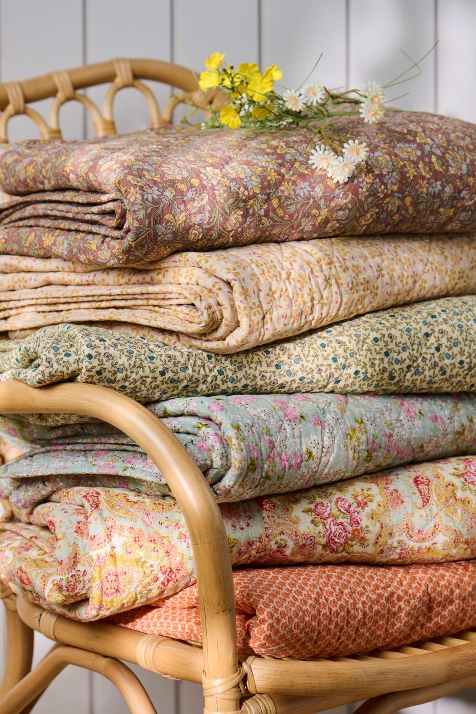 Foldede quilts fra Ib Laursen i ulike tekstiler med blomster- og mønstertrykk i varme farger