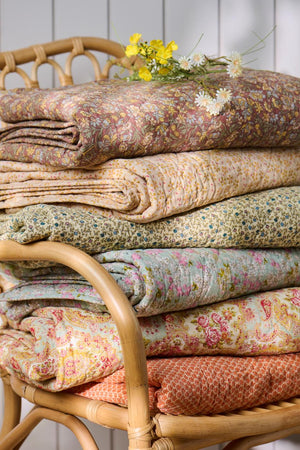 Foldede quilts fra Ib Laursen i ulike tekstiler med blomster- og mønstertrykk i varme farger