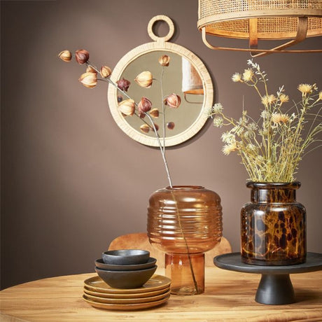 Rundt Kaj spejl med ratan ramme på grå væg med tørrede blomster i vaser i forgrunden