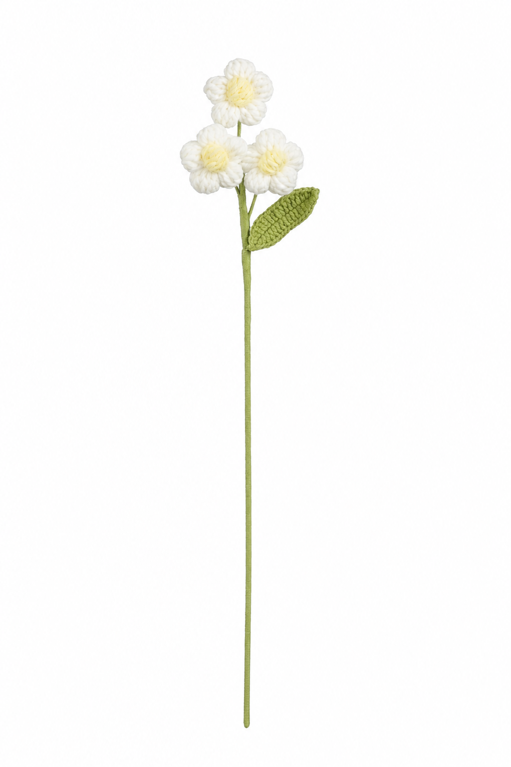 Hvit heklet blomststilk med tre små blomster, gul midte og grønt blad
