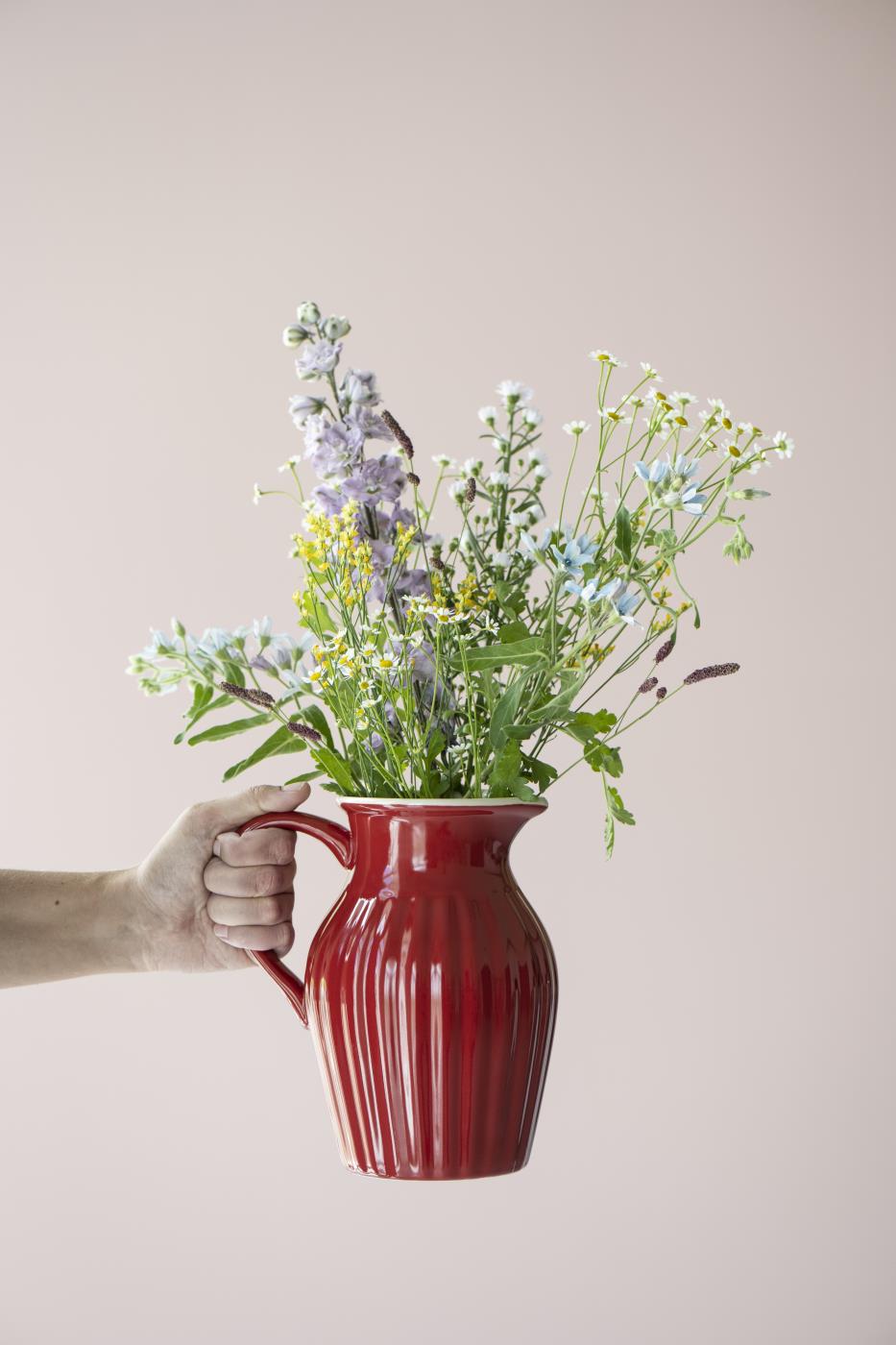 Myntekande i jordbærfarge brukt som vase med lilla og hvite sommerblomster