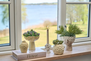 Vase i lysegul keramik med blomstermønster pynter i en vindueskarm
