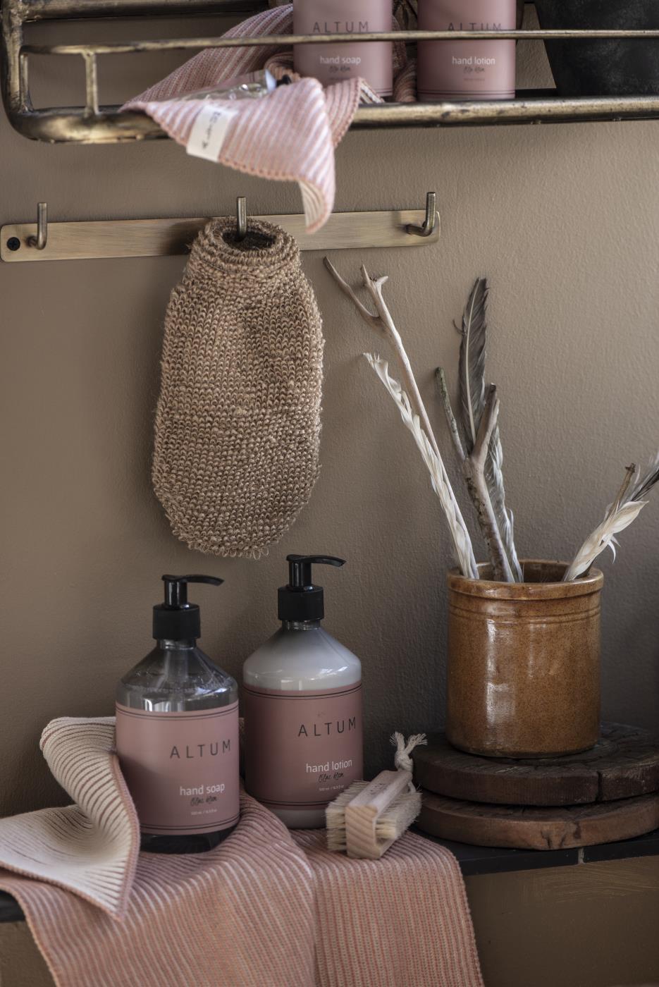 Badehanske i jute henger på badet sammen med såper og pleieprodukter fra Ib Laursens ALTUM-serie.