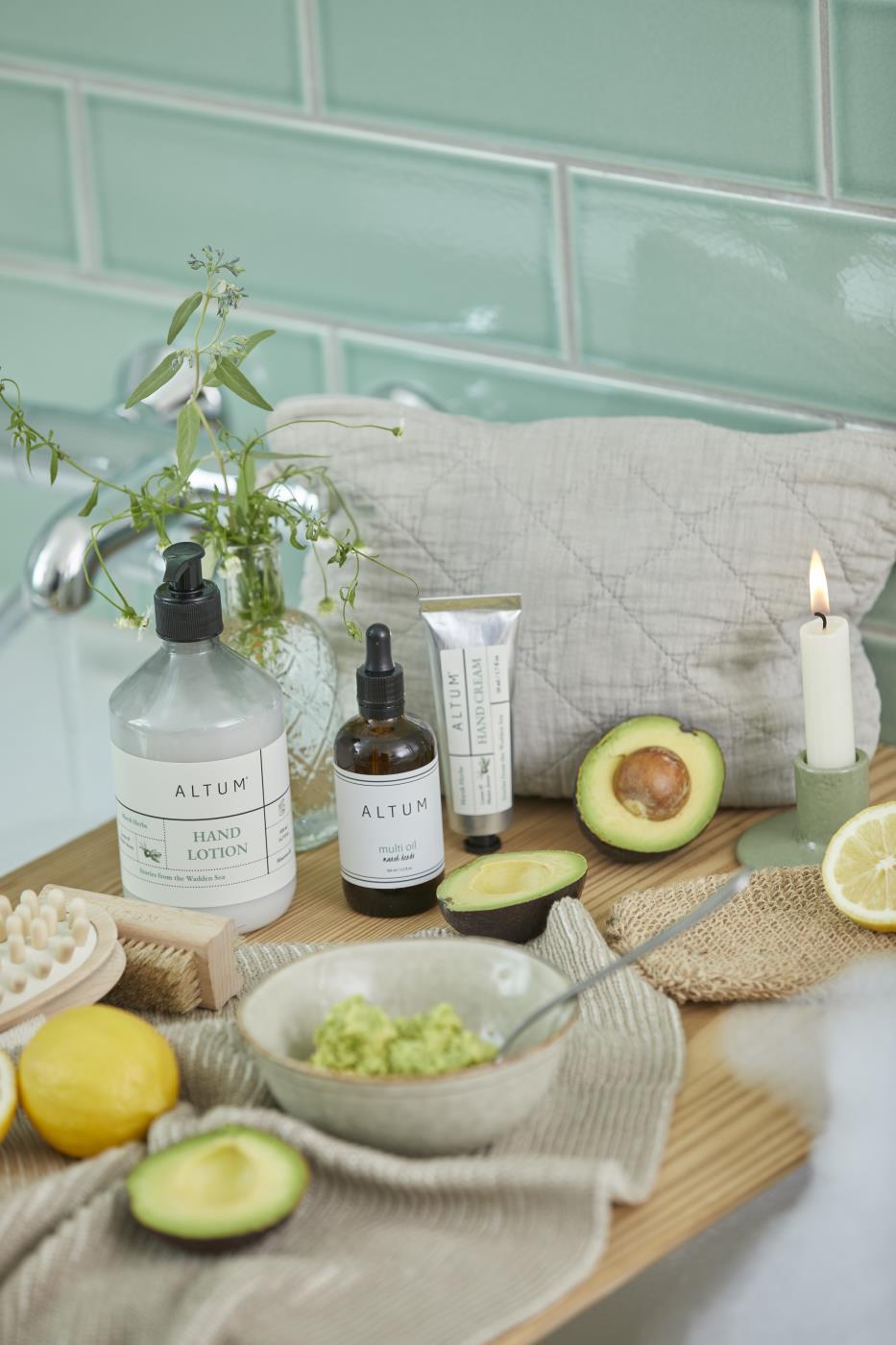 Baderomsmiljø med naturlige pleieprodukter, avokado og ALTUM badehanske i jute til kroppspleie.