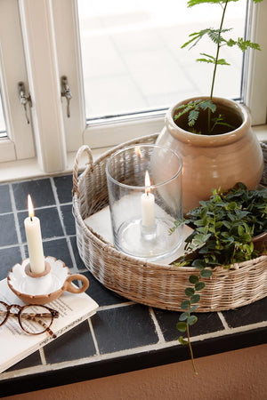 Bred glasslysestake med kronelys på brett i vinduskarmen sammen med grønne planter og naturpynt